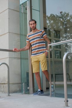 Güzel çocuk bermuda şortu ve çizgili gömleğiyle geziniyor. Yüksek kalite fotoğraf