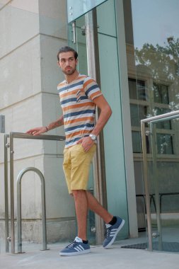 Güzel çocuk bermuda şortu ve çizgili gömleğiyle geziniyor. Yüksek kalite fotoğraf