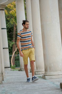 Güzel çocuk bermuda şortu ve çizgili gömleğiyle geziniyor. Yüksek kalite fotoğraf