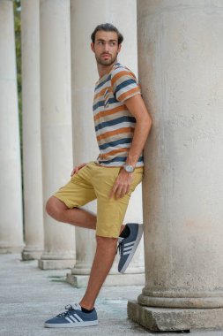 Güzel çocuk bermuda şortu ve çizgili gömleğiyle geziniyor. Yüksek kalite fotoğraf