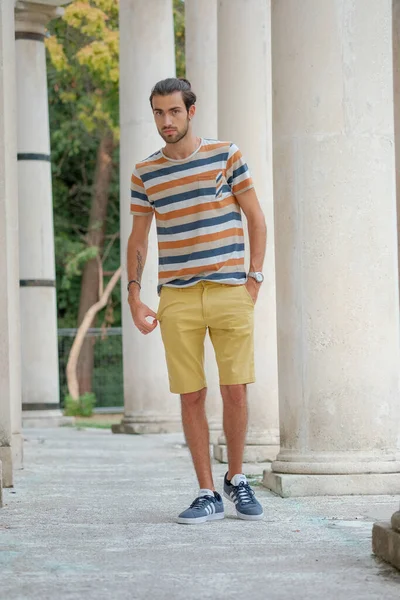 Güzel çocuk bermuda şortu ve çizgili gömleğiyle geziniyor. Yüksek kalite fotoğraf