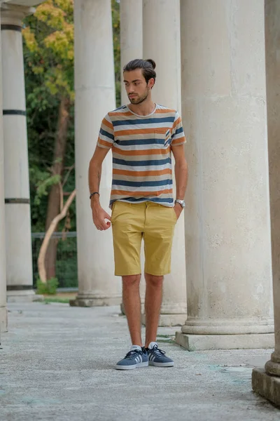 Güzel çocuk bermuda şortu ve çizgili gömleğiyle geziniyor. Yüksek kalite fotoğraf