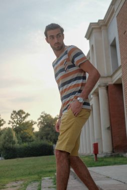 Güzel çocuk bermuda şortu ve çizgili gömleğiyle geziniyor. Yüksek kalite fotoğraf