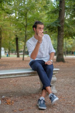 Parma 'daki Ducale parkındaki bankta oturan siyah tişörtlü yakışıklı İtalyan çocuk. Yüksek kalite fotoğraf