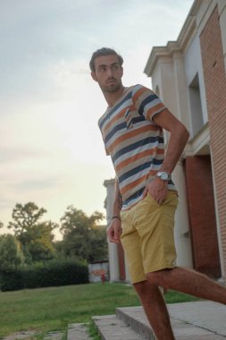 Güzel çocuk bermuda şortu ve çizgili gömleğiyle geziniyor. Yüksek kalite fotoğraf