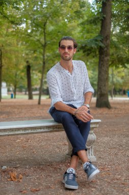 Parma 'daki Ducale parkındaki bankta oturan siyah tişörtlü yakışıklı İtalyan çocuk. Yüksek kalite fotoğraf