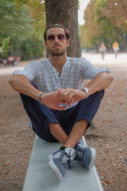 Parma 'daki Ducale parkındaki bankta oturan siyah tişörtlü yakışıklı İtalyan çocuk. Yüksek kalite fotoğraf