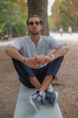 Parma 'daki Ducale parkındaki bankta oturan siyah tişörtlü yakışıklı İtalyan çocuk. Yüksek kalite fotoğraf