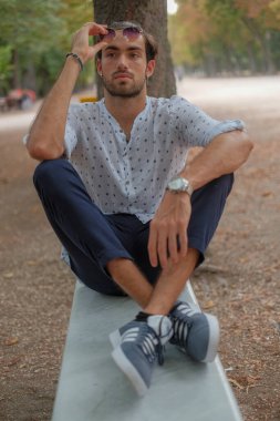 Parma 'daki Ducale parkındaki bankta oturan siyah tişörtlü yakışıklı İtalyan çocuk. Yüksek kalite fotoğraf