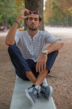 Parma 'daki Ducale parkındaki bankta oturan siyah tişörtlü yakışıklı İtalyan çocuk. Yüksek kalite fotoğraf