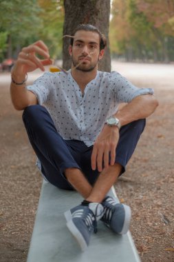 Parma 'daki Ducale parkındaki bankta oturan siyah tişörtlü yakışıklı İtalyan çocuk. Yüksek kalite fotoğraf