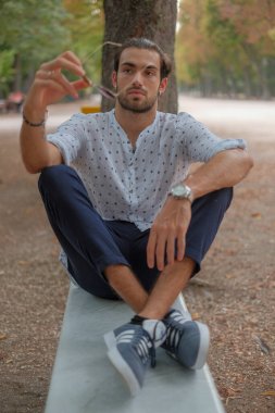 Parma 'daki Ducale parkındaki bankta oturan siyah tişörtlü yakışıklı İtalyan çocuk. Yüksek kalite fotoğraf