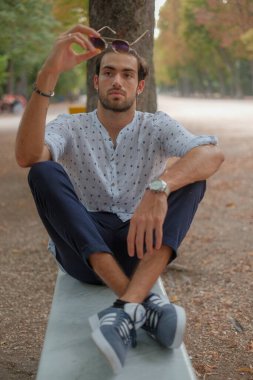 Parma 'daki Ducale parkındaki bankta oturan siyah tişörtlü yakışıklı İtalyan çocuk. Yüksek kalite fotoğraf