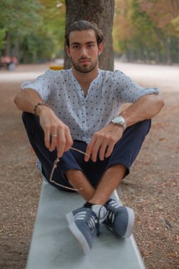 Parma 'daki Ducale parkındaki bankta oturan siyah tişörtlü yakışıklı İtalyan çocuk. Yüksek kalite fotoğraf