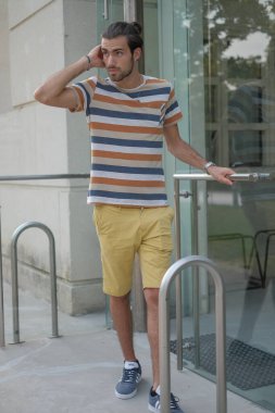 Güzel çocuk bermuda şortu ve çizgili gömleğiyle geziniyor. Yüksek kalite fotoğraf