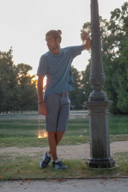 Parma 'daki Ducal Park' ın direğine yaslanmış yakışıklı siyah saçlı çocuk. Yüksek kalite fotoğraf