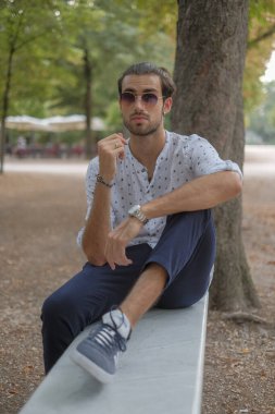 Parma 'daki Ducale parkındaki bankta oturan siyah tişörtlü yakışıklı İtalyan çocuk. Yüksek kalite fotoğraf