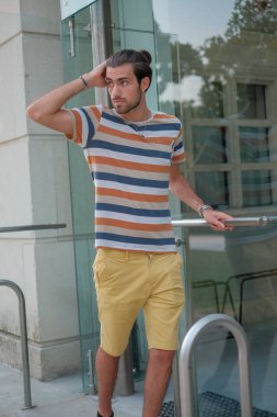 Güzel çocuk bermuda şortu ve çizgili gömleğiyle geziniyor. Yüksek kalite fotoğraf