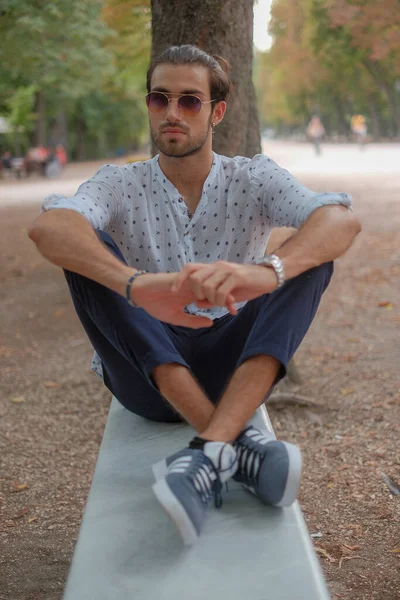 Parma 'daki Ducale parkındaki bankta oturan siyah tişörtlü yakışıklı İtalyan çocuk. Yüksek kalite fotoğraf