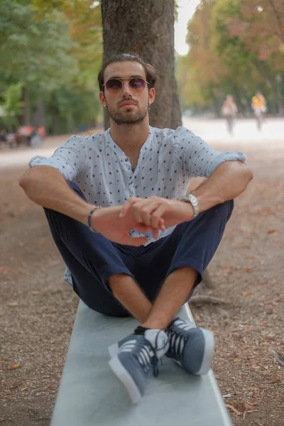 Parma 'daki Ducale parkındaki bankta oturan siyah tişörtlü yakışıklı İtalyan çocuk. Yüksek kalite fotoğraf