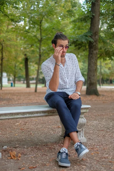 Parma 'daki Ducale parkındaki bankta oturan siyah tişörtlü yakışıklı İtalyan çocuk. Yüksek kalite fotoğraf