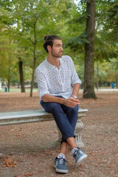 Parma 'daki Ducale parkındaki bankta oturan siyah tişörtlü yakışıklı İtalyan çocuk. Yüksek kalite fotoğraf