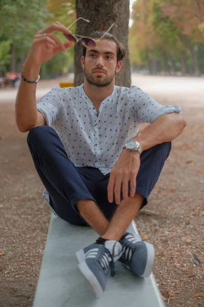 Parma 'daki Ducale parkındaki bankta oturan siyah tişörtlü yakışıklı İtalyan çocuk. Yüksek kalite fotoğraf