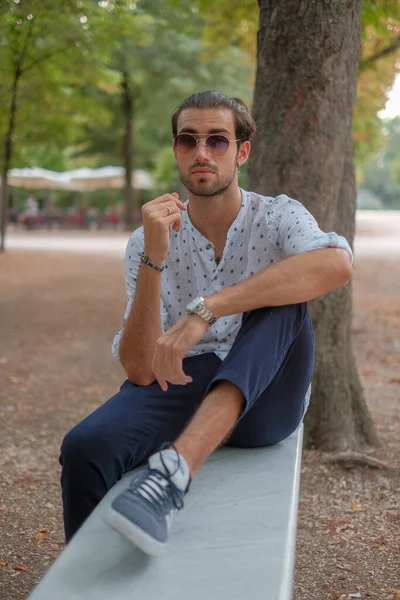 Parma 'daki Ducale parkındaki bankta oturan siyah tişörtlü yakışıklı İtalyan çocuk. Yüksek kalite fotoğraf