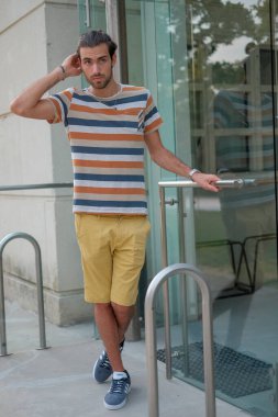 Güzel çocuk bermuda şortu ve çizgili gömleğiyle geziniyor. Yüksek kalite fotoğraf