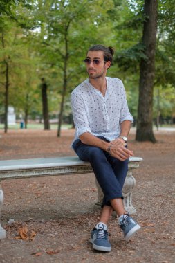 Parma 'daki Ducale parkındaki bankta oturan siyah tişörtlü yakışıklı İtalyan çocuk. Yüksek kalite fotoğraf