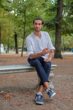 Parma 'daki Ducale parkındaki bankta oturan siyah tişörtlü yakışıklı İtalyan çocuk. Yüksek kalite fotoğraf