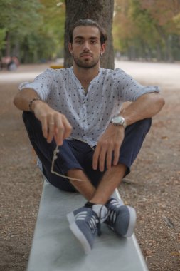 Parma 'daki Ducale parkındaki bankta oturan siyah tişörtlü yakışıklı İtalyan çocuk. Yüksek kalite fotoğraf