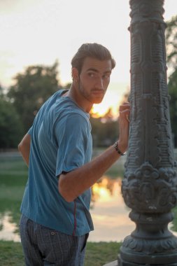 Parma 'daki Ducal Park' ın direğine yaslanmış yakışıklı siyah saçlı çocuk. Yüksek kalite fotoğraf