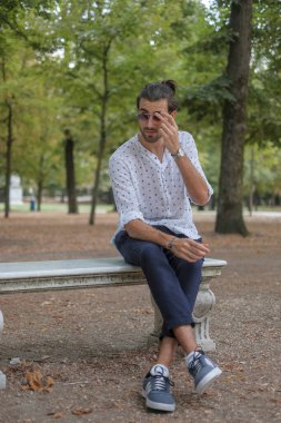 Parma 'daki Ducale parkındaki bankta oturan siyah tişörtlü yakışıklı İtalyan çocuk. Yüksek kalite fotoğraf