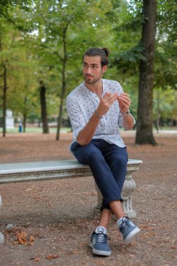 Parma 'daki Ducale parkındaki bankta oturan siyah tişörtlü yakışıklı İtalyan çocuk. Yüksek kalite fotoğraf