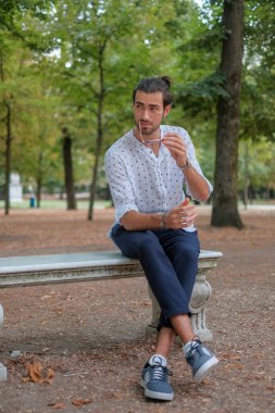 Parma 'daki Ducale parkındaki bankta oturan siyah tişörtlü yakışıklı İtalyan çocuk. Yüksek kalite fotoğraf