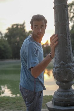 Parma 'daki Ducal Park' ın direğine yaslanmış yakışıklı siyah saçlı çocuk. Yüksek kalite fotoğraf