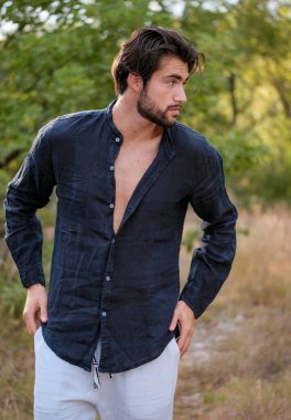 Kuru çimenlerde gömleği olan yakışıklı, siyah saçlı bir İtalyan. Yüksek kalite fotoğraf