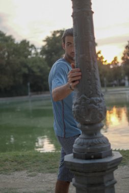 Parma 'daki Ducal Park' ın direğine yaslanmış yakışıklı siyah saçlı çocuk. Yüksek kalite fotoğraf