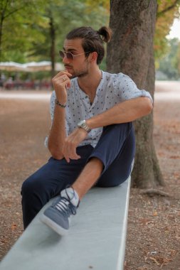 Parma 'daki Ducale parkındaki bankta oturan siyah tişörtlü yakışıklı İtalyan çocuk. Yüksek kalite fotoğraf