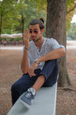 Parma 'daki Ducale parkındaki bankta oturan siyah tişörtlü yakışıklı İtalyan çocuk. Yüksek kalite fotoğraf