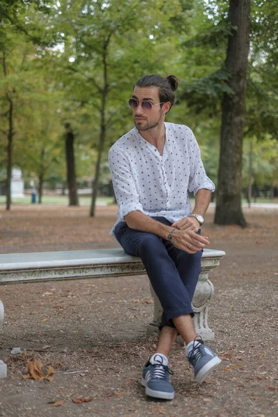 Parma 'daki Ducale parkındaki bankta oturan siyah tişörtlü yakışıklı İtalyan çocuk. Yüksek kalite fotoğraf