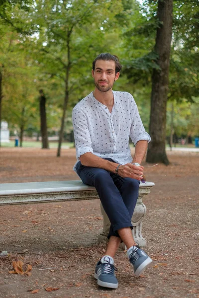 Parma 'daki Ducale parkındaki bankta oturan siyah tişörtlü yakışıklı İtalyan çocuk. Yüksek kalite fotoğraf