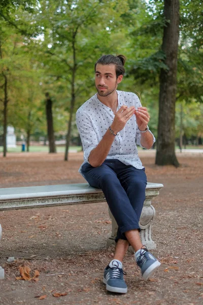 Parma 'daki Ducale parkındaki bankta oturan siyah tişörtlü yakışıklı İtalyan çocuk. Yüksek kalite fotoğraf