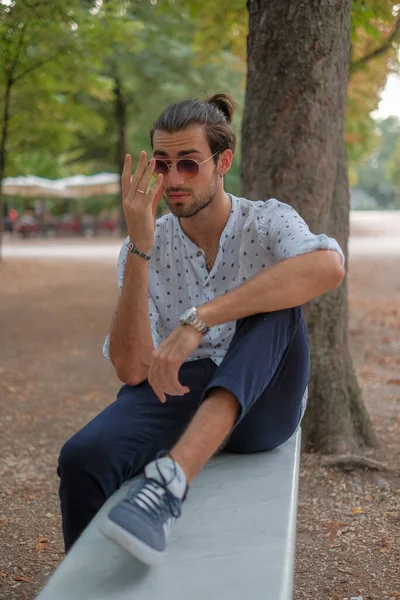 Parma 'daki Ducale parkındaki bankta oturan siyah tişörtlü yakışıklı İtalyan çocuk. Yüksek kalite fotoğraf