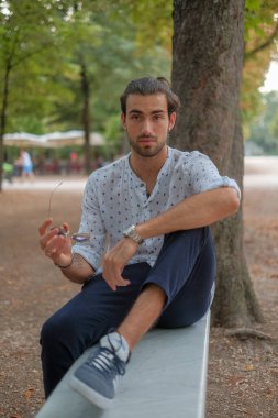 Parma 'daki Ducale parkındaki bankta oturan siyah tişörtlü yakışıklı İtalyan çocuk. Yüksek kalite fotoğraf