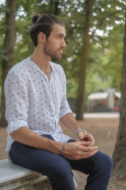 Parma 'daki Ducale parkındaki bankta oturan siyah tişörtlü yakışıklı İtalyan çocuk. Yüksek kalite fotoğraf