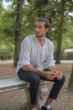 Parma 'daki Ducale parkındaki bankta oturan siyah tişörtlü yakışıklı İtalyan çocuk. Yüksek kalite fotoğraf