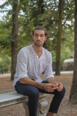 Parma 'daki Ducale parkındaki bankta oturan siyah tişörtlü yakışıklı İtalyan çocuk. Yüksek kalite fotoğraf