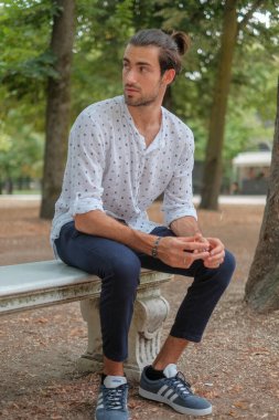 Parma 'daki Ducale parkındaki bankta oturan siyah tişörtlü yakışıklı İtalyan çocuk. Yüksek kalite fotoğraf